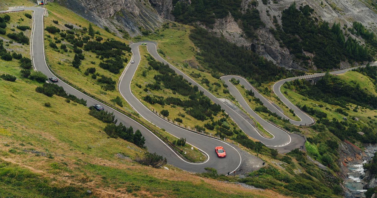 Stelvio Pass is known for its tight, twisting and technical corners. A convoy of supercars ascend the many steep hairpin bends of Stelvio Pass, Italy
