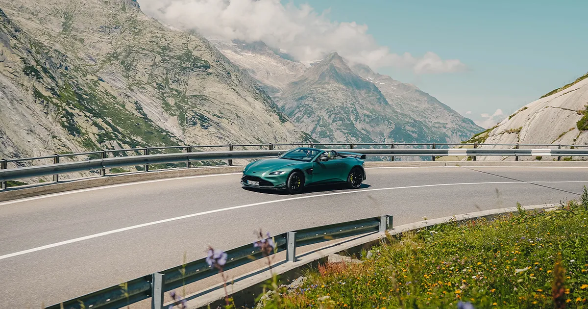 A teal coloured Aston Martin Vantage F1 Roadster rounds a corner during an HunterMoss luxury tour.