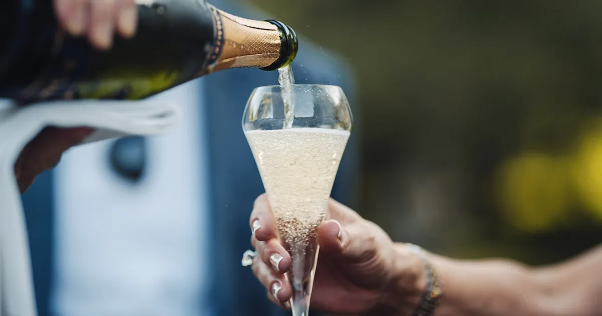A flute being filled with cold Champagne.
