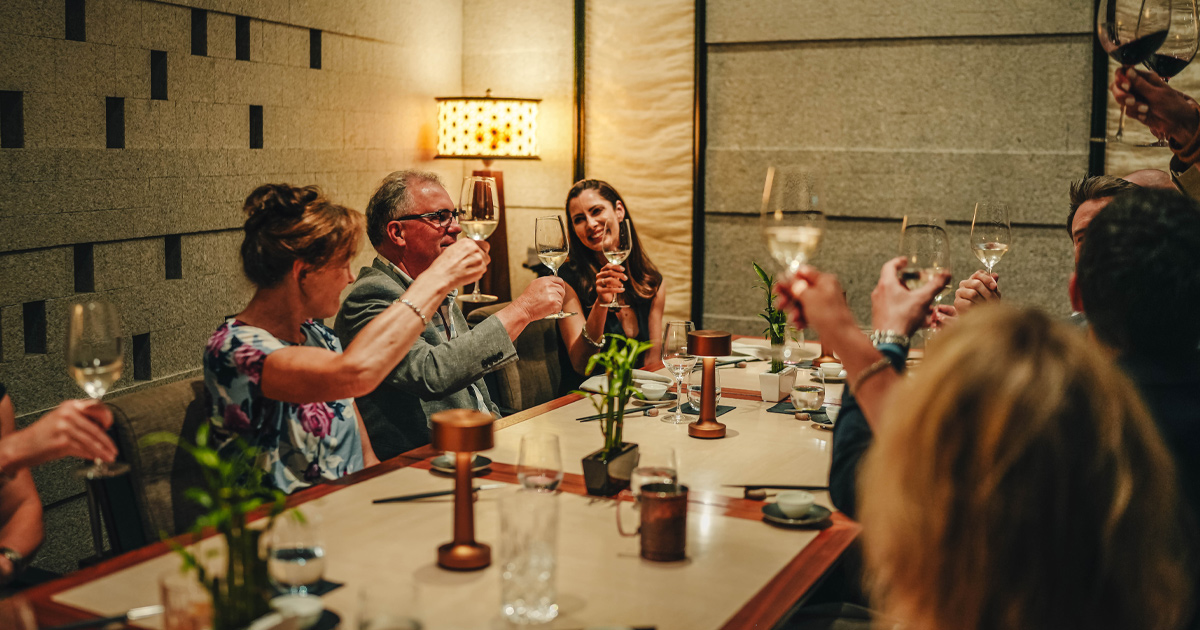 An HunterMoss group of guests shares a toast around an elegant dinner table at a fine dining restaurant