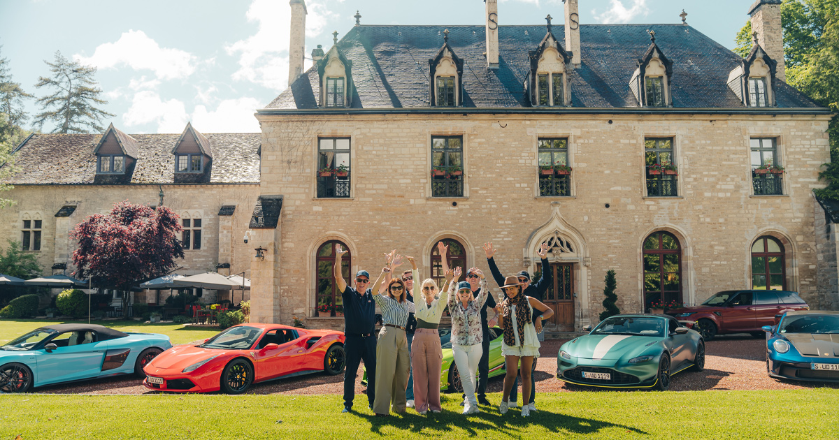 HunterMoss guests with hands raised in celebration outside a historic country estate in France