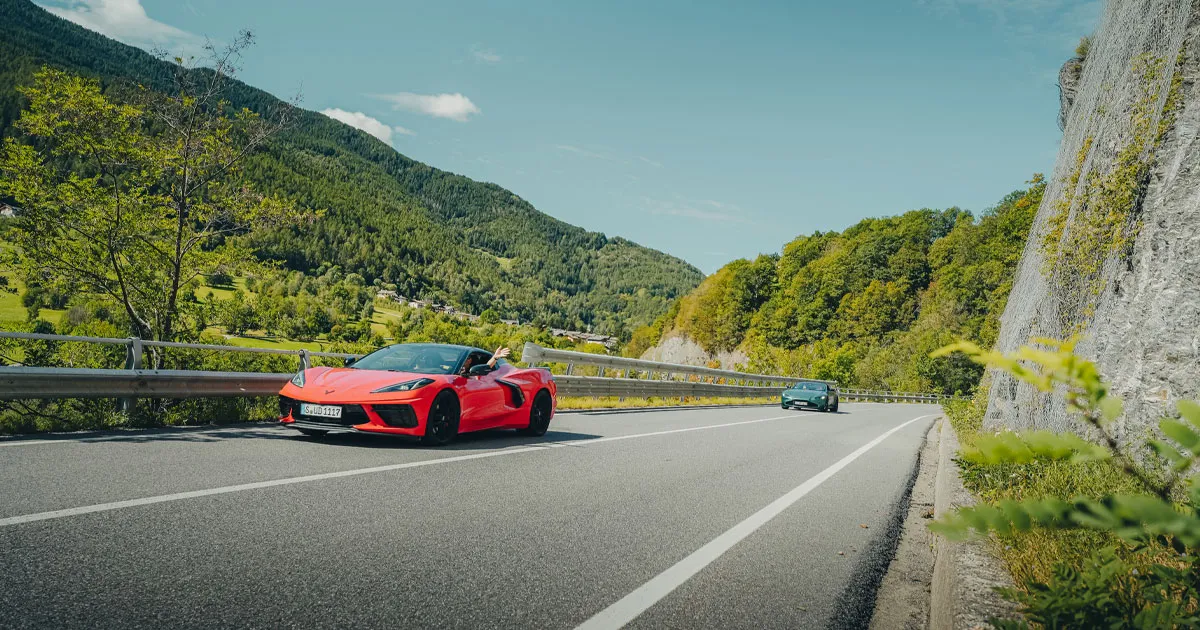 An orange Chevrolet Corvette leads a green Aston Martin on an HunterMoss experience.