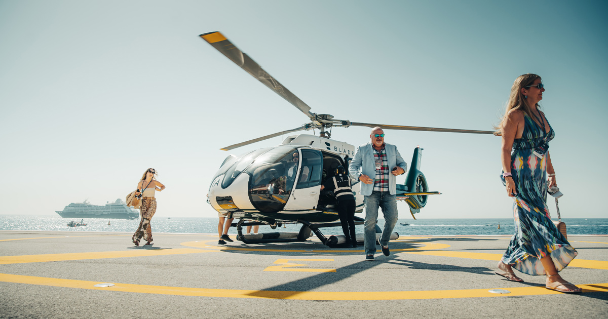 A man and two women walking away from a helicopter as part of a HM luxury tour
