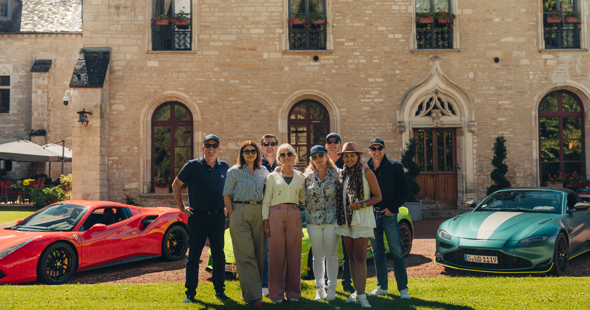 A group of HunterMoss guests pose happily in front of a chateau