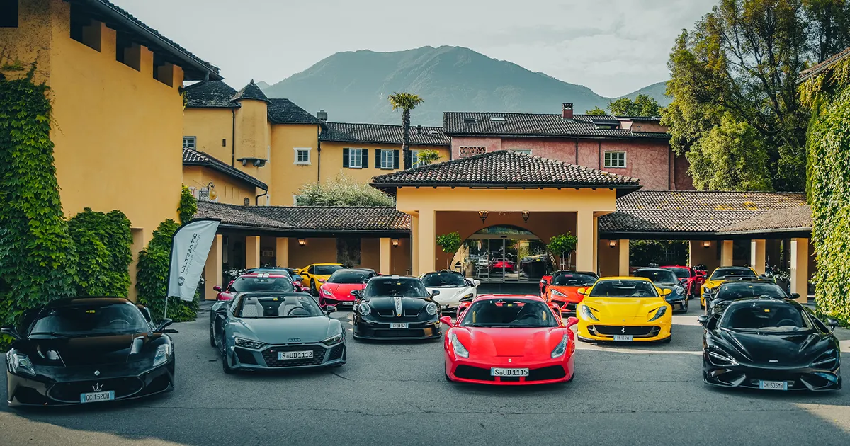 The HunterMoss fleet of supercars sits outside a brightly coloured European luxury villa.