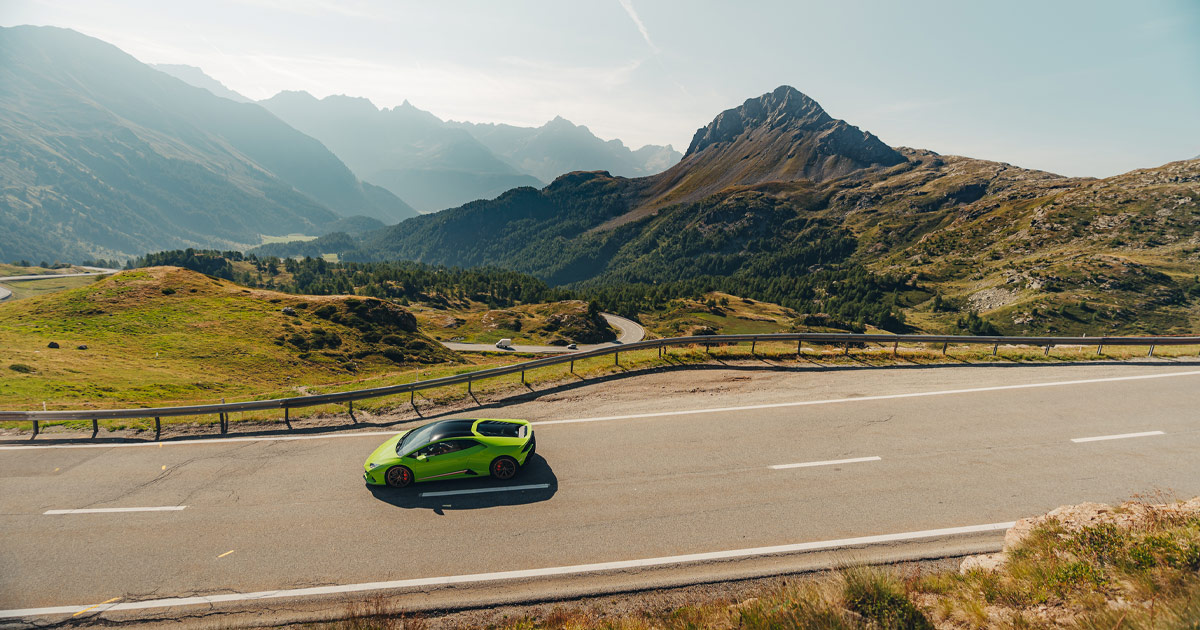 A bright green Lamborghini Huracan cruising along a mountain road in Europe