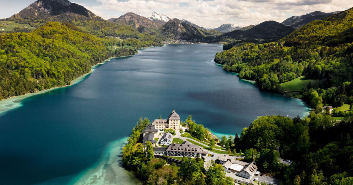 A grand resort sits on the banks of the deep blue waters of Lake Fuschl, Austria
