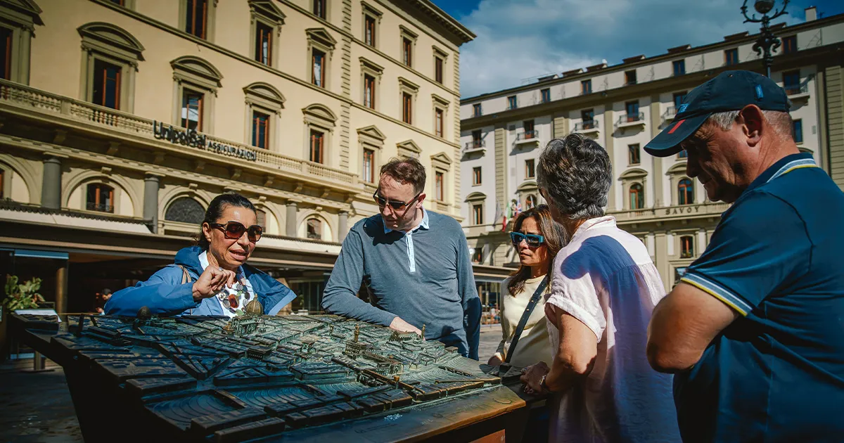 A female tour guide explains an ornate map to a small group of HunterMoss guests.