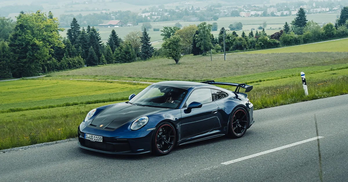 A blue Porsche 911 GT3 driving on a country road during an HunterMoss luxury holiday.