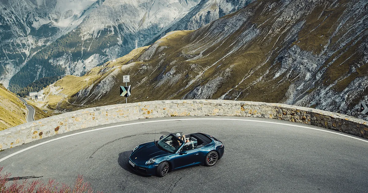A convertible Porsche 911 rounds a bend in the mountains on an HunterMoss supercar tour.