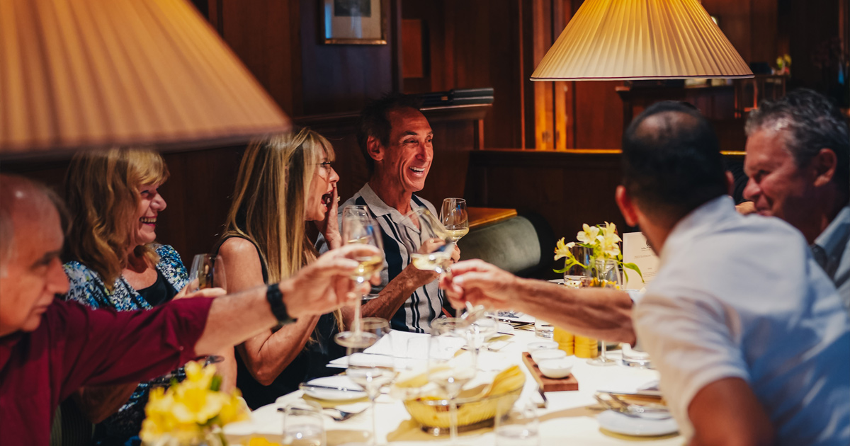 A group of guests share happy conversation around the dining table during an HunterMoss experience.