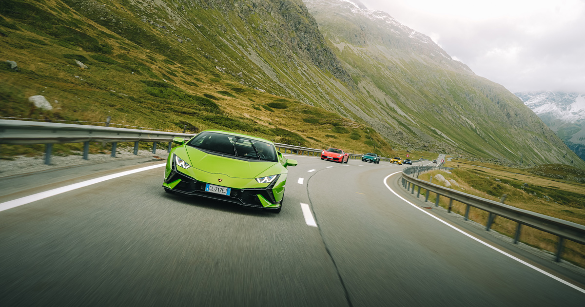 A green Lamborghini Huracan leading a convoy of supercars on an alpine road as part of an HunterMoss tour