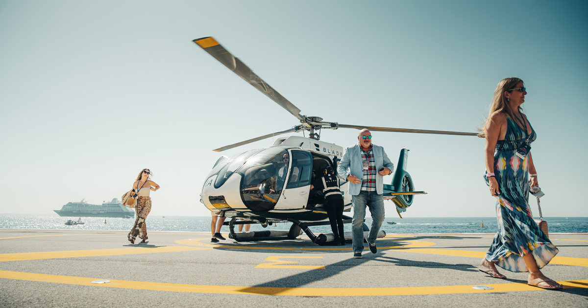 A small group disembarking from a helicopter on a sunny day as part of a HM luxury tour