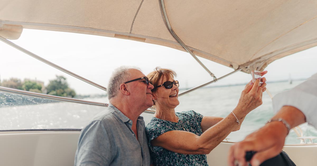 A happy elderly couple snap a selfie on a boat in Europe