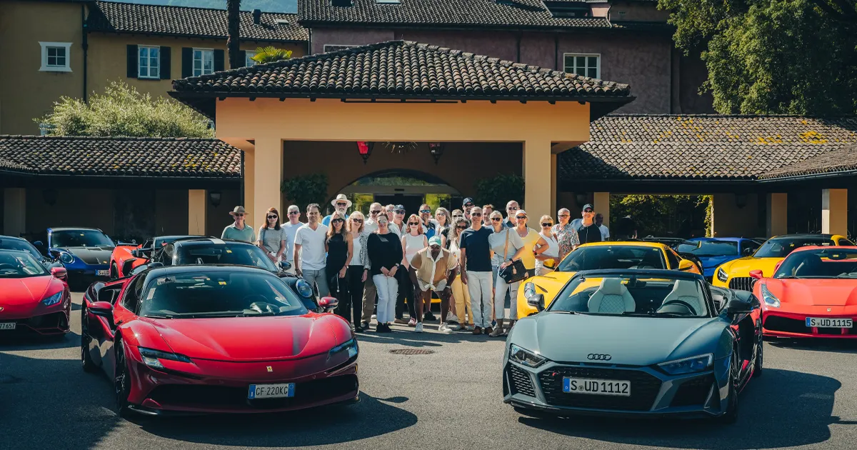 A group of people stand outside a luxury villa flanked by HunterMoss supercars