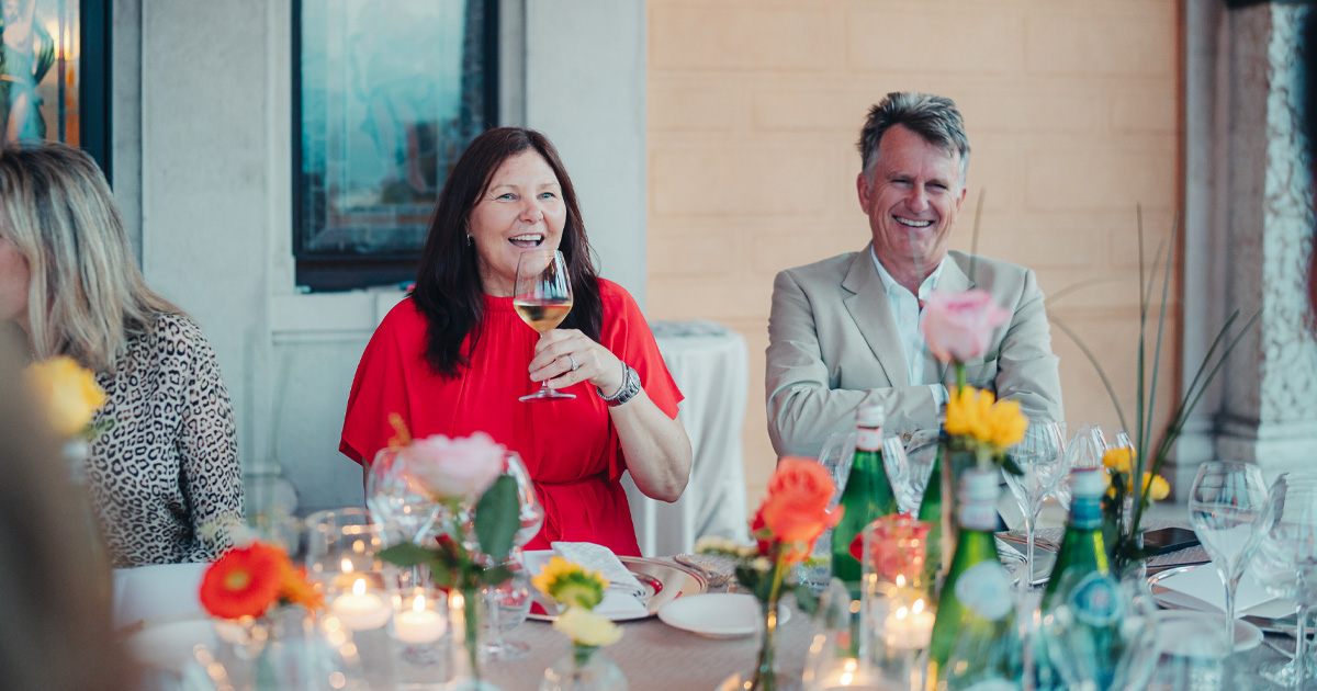 A smartly dressed woman and man enjoy a laugh during a luxury tour lunch