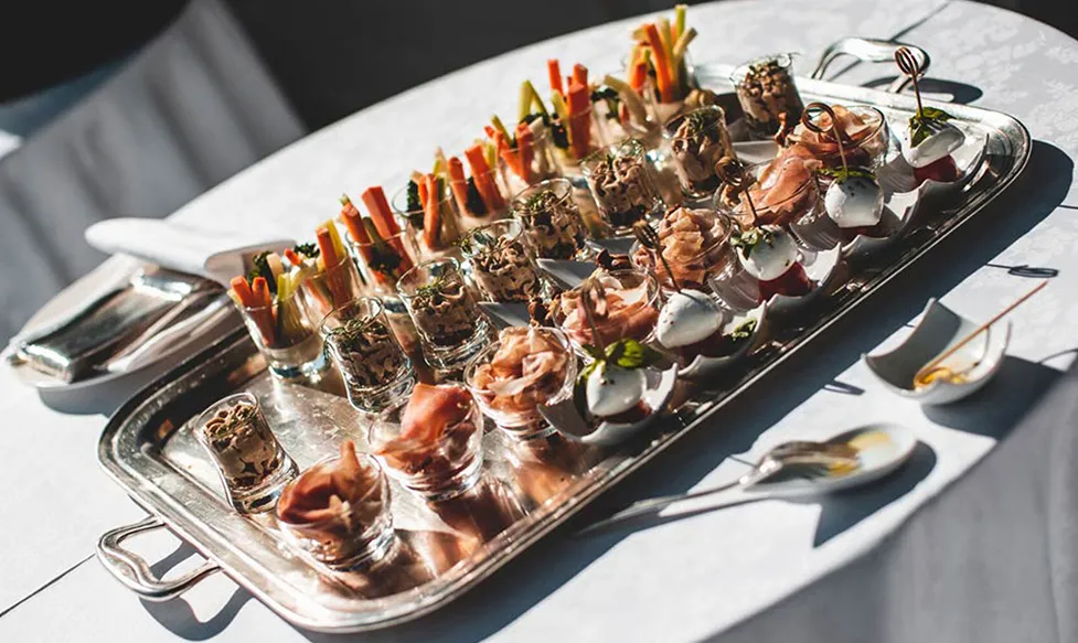 A silver platter holds delicate canapés in decorative glasses ready for serving to HunterMoss’; guests in Italy