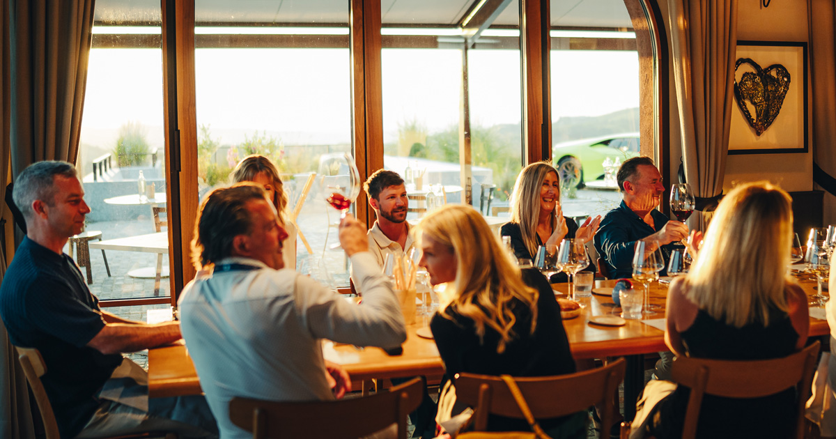 A group of luxury tour guests share a toast at a large elegant dining table in Europe