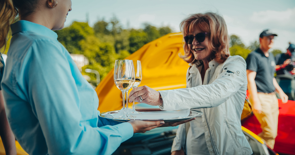 A lady in sunglasses is served a glass of wine as part of a luxury European tour