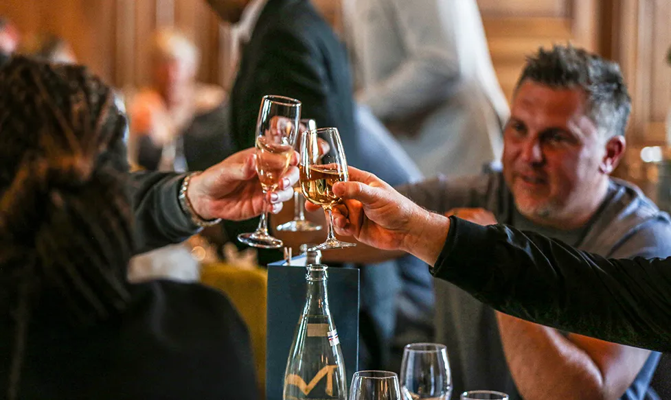 Three people toast glasses of champagne on a luxury holiday with HunterMoss.