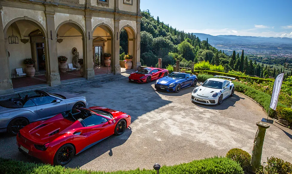 The HunterMoss fleet of supercars sits outside a quintessential Tuscan luxury villa on a sunny day