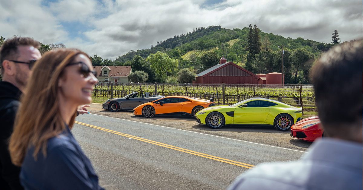 Julie Hunter and Anthony Moss of HunterMoss watch on as supercar tour guests arrive at their destination