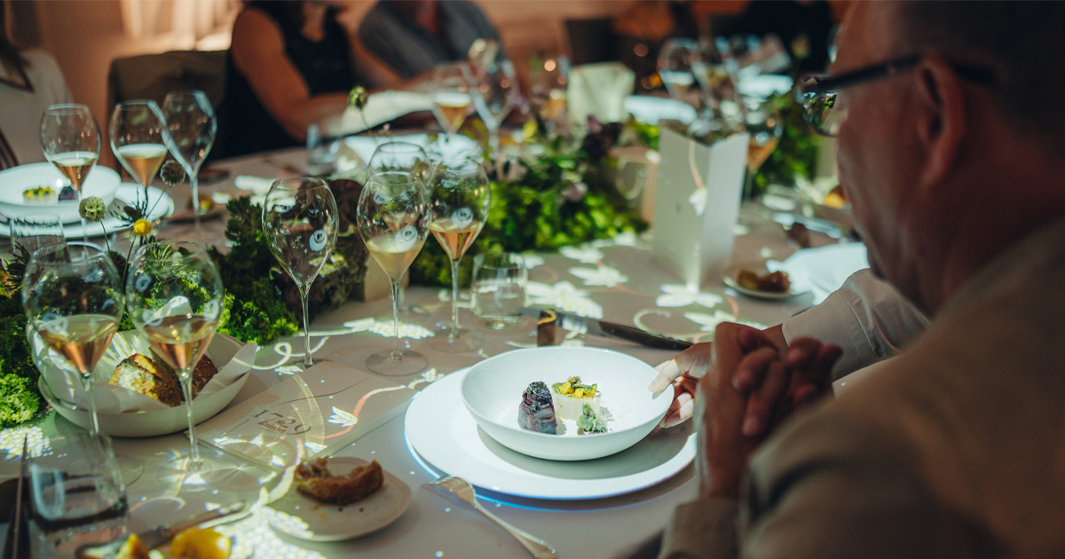 A man is served an entree with sparkling wine on at a lavish dining table