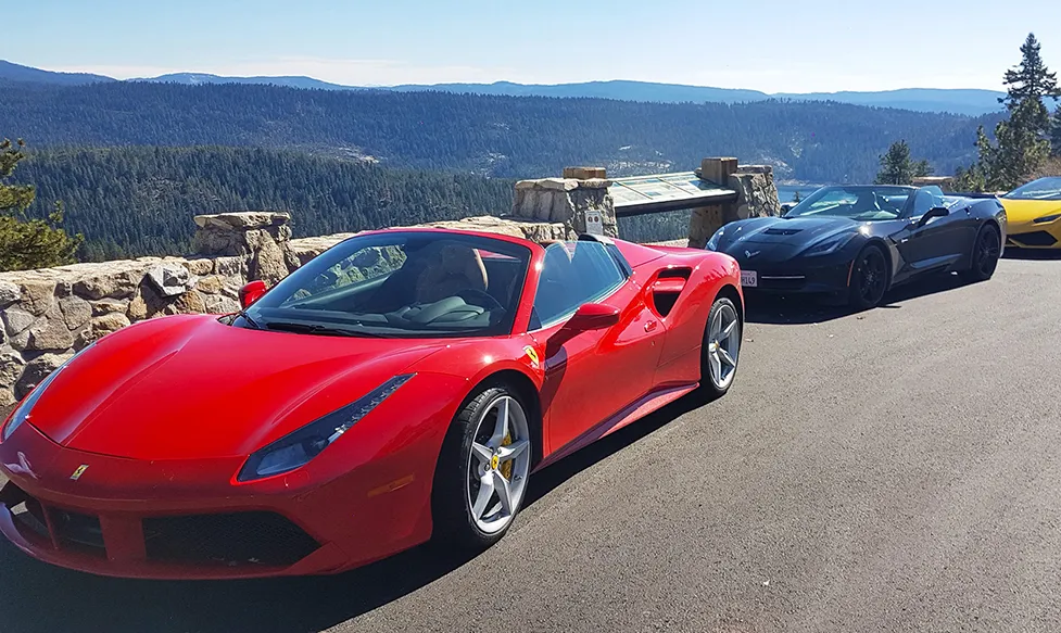 A red Ferrari convertible sits with a black Chevrolet Corvette on an HunterMoss luxury escape