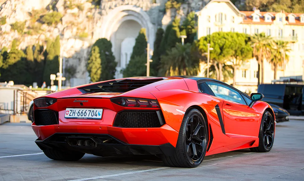 A red Lamborghini Aventador is seen from the rear as it drives through Monaco on an HunterMoss luxury holiday
