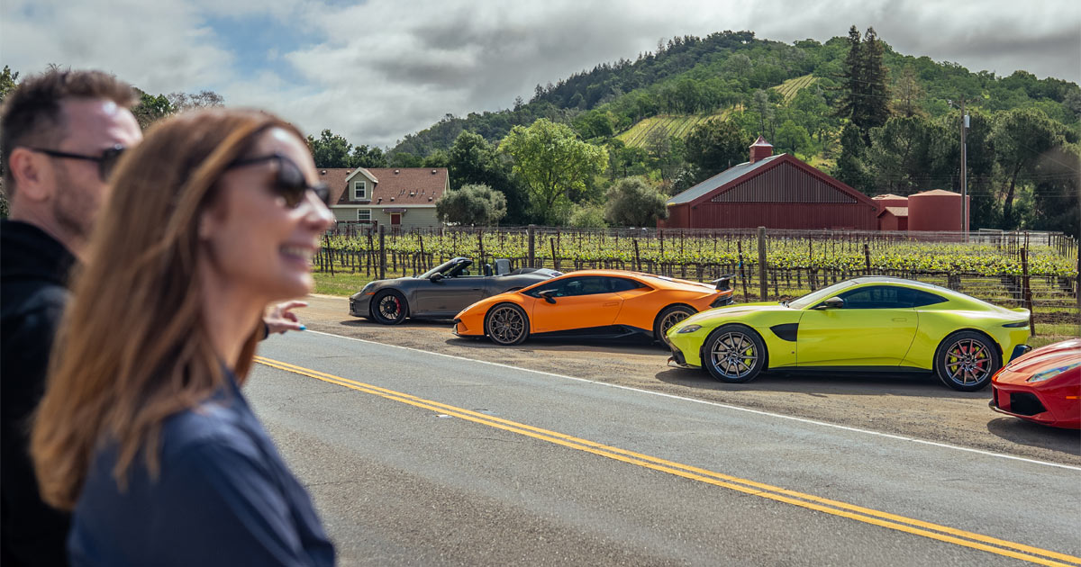 Anthony Moss and Julie Hunter of HunterMoss look across a road at their supercar fleet during a tour.